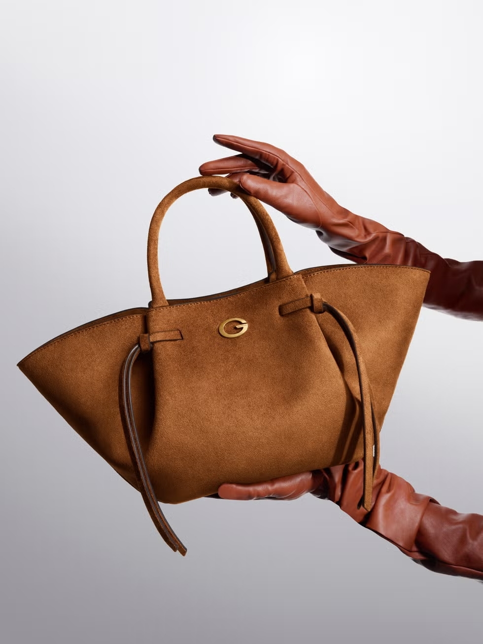 GUESS-Kampagne: Model in Lederjacke mit GUESS-Handtasche auf einem silbernen Oldtimer